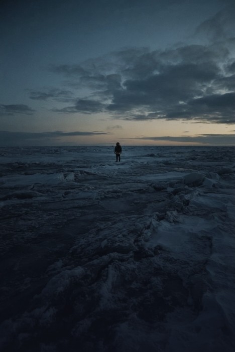 A lone figure on an Arctic ice field at dusk