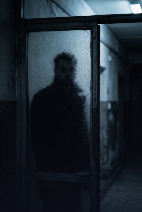 A shadowed figure behind frosted glass